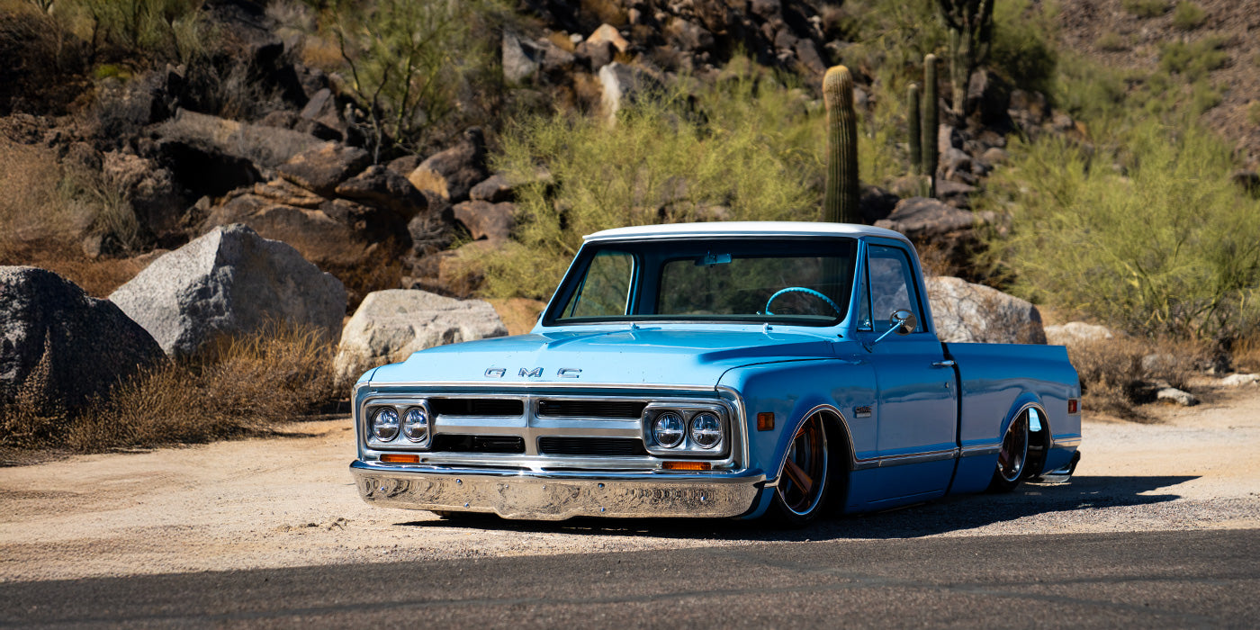 Vintage blue truck on a desert road with cacti and rocks in the background